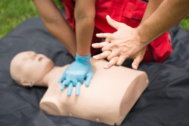 Foto manos cortadas de un hombre instruyendo a un paramédico practicando rcp en un maniquí