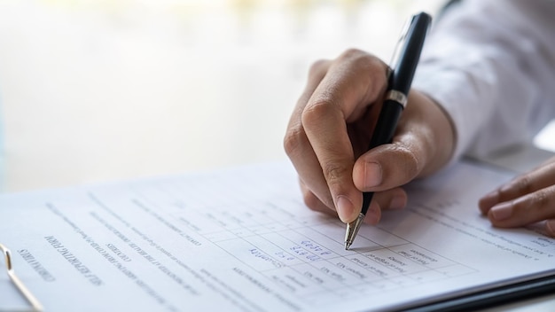 Manos cortadas de un hombre llenando un formulario en un escritorio en un hospital