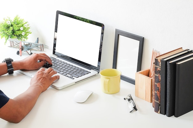 Manos cortadas de un hombre de negocios usando una computadora portátil en el escritorio de la oficina