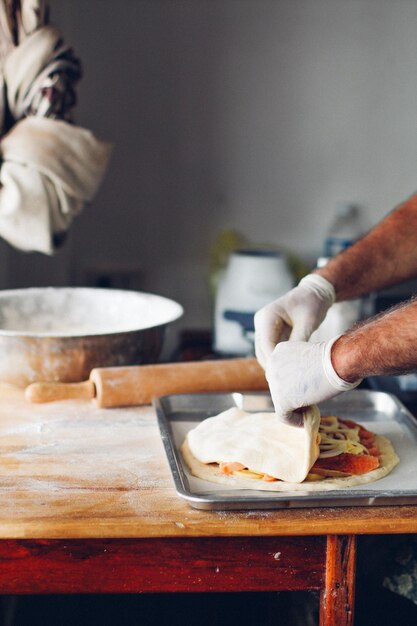 Manos cortadas de un hombre preparando comida en la cocina