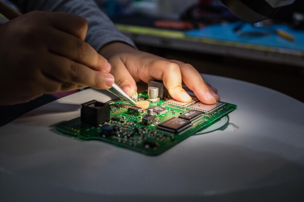 Manos cortadas de un hombre reparando la placa base en la mesa