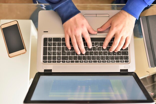 Manos cortadas de un hombre usando una computadora portátil en la mesa