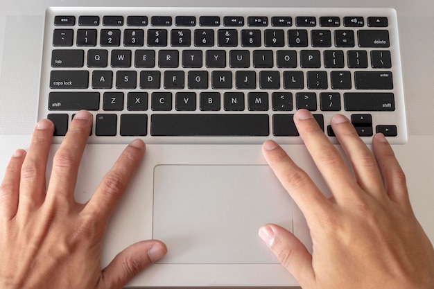 Manos cortadas de un hombre usando una computadora portátil