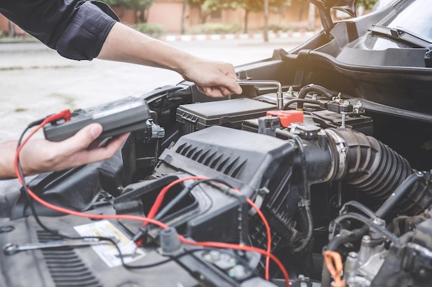 Manos cortadas de un mecánico reparando el motor de un coche