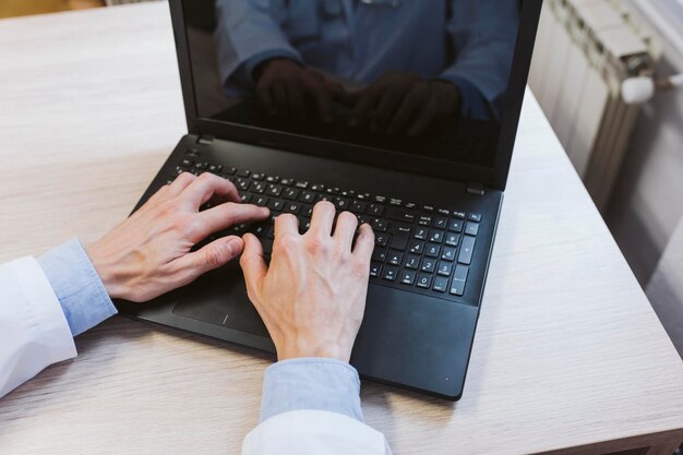 Manos cortadas de un médico usando una computadora portátil en la mesa