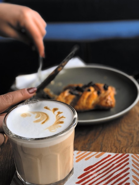 Manos cortadas de una mujer con comida y café en la mesa