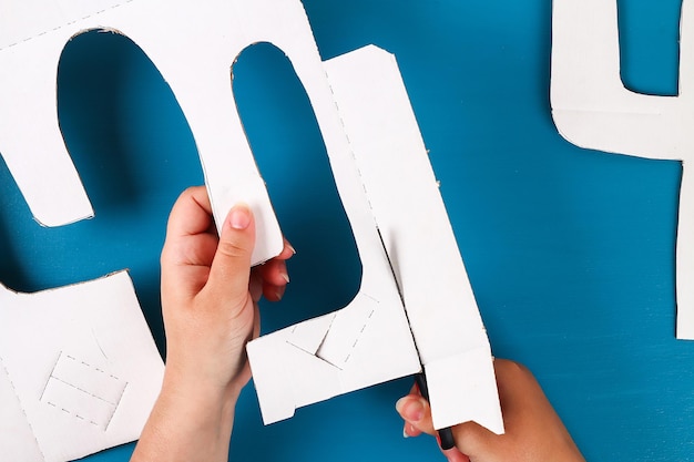 Manos cortadas de una mujer cortando papel en la mesa
