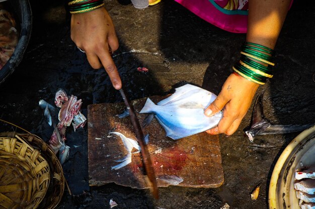 Foto manos cortadas de una mujer cortando pescado en el mercado