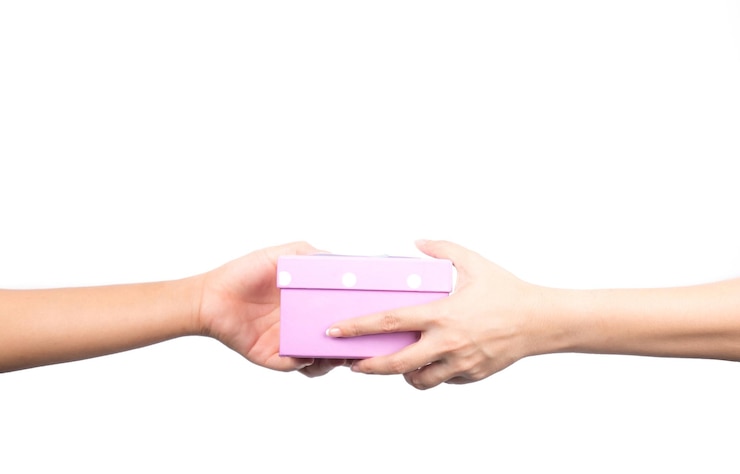 Foto manos cortadas de una mujer dando un regalo de navidad a una amiga contra un fondo blanco