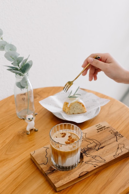 Manos cortadas de una mujer desayunando en la mesa.