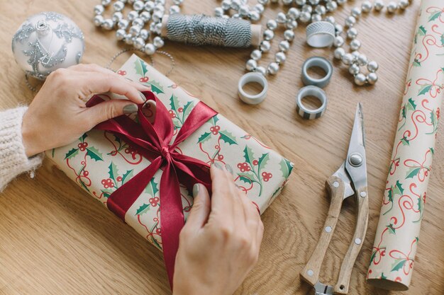 Foto manos cortadas de una mujer envolviendo regalos en la mesa en casa