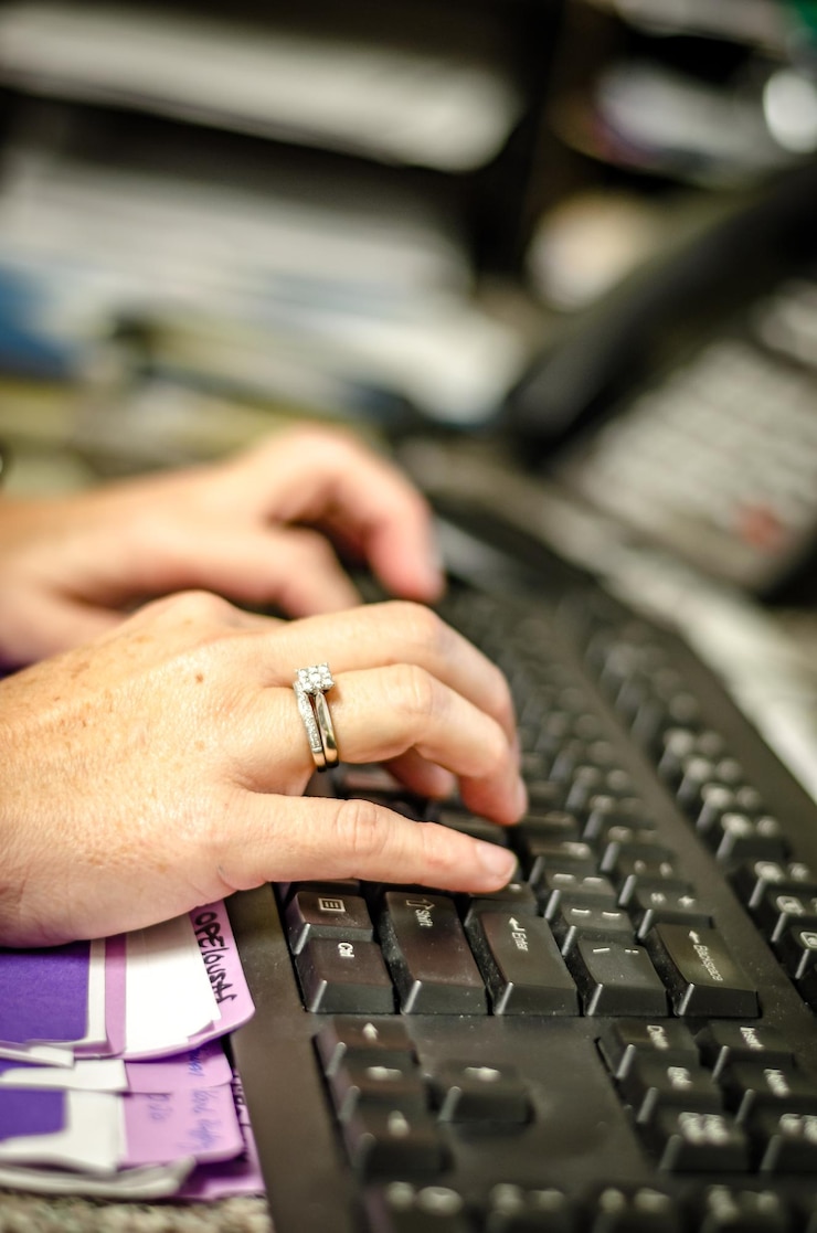 Foto manos cortadas de una mujer escribiendo en el teclado en el escritorio