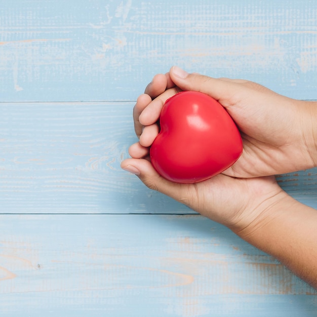 Foto manos cortadas de una mujer con forma de corazón rojo sobre la mesa