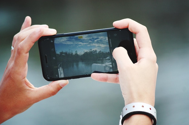 Manos cortadas de una mujer fotografiando a través de un teléfono móvil