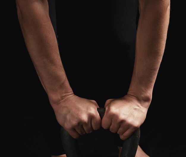 Foto manos cortadas de una mujer con kettlebell contra un fondo negro