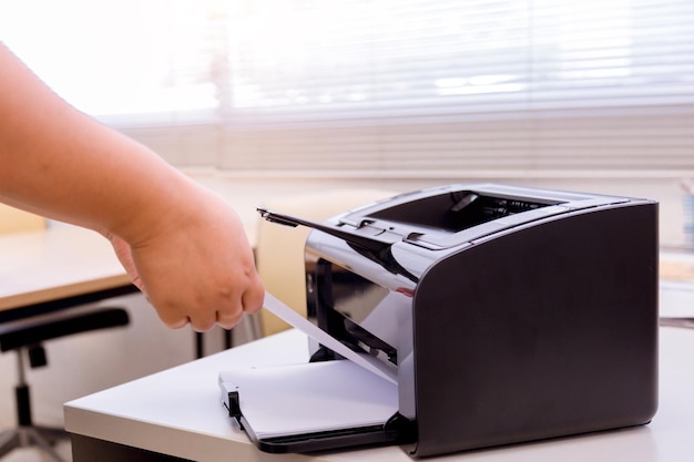 Foto manos cortadas de una mujer de negocios usando una impresora de computadora en la mesa de la oficina