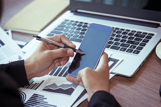 Manos cortadas de una mujer de negocios usando teléfono móvil en la oficina