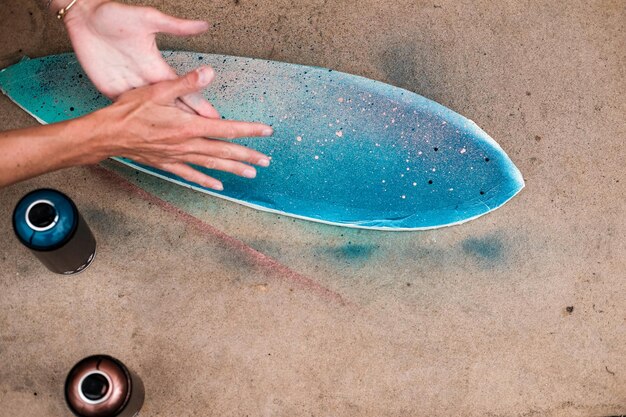 Foto manos cortadas de una mujer pintando patineta