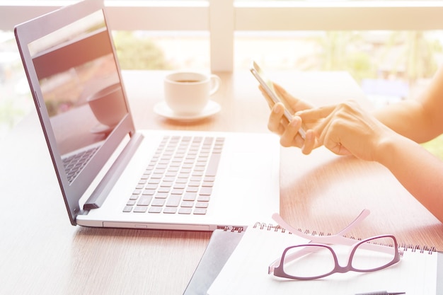 Foto manos cortadas de una mujer usando tecnologías en la mesa