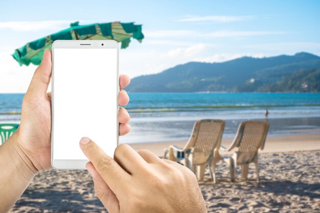 Foto manos cortadas de una mujer usando un teléfono móvil en la playa contra el cielo