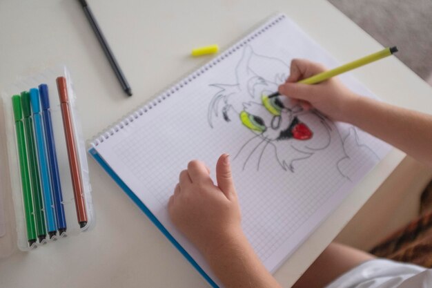 Manos cortadas de un niño dibujando en un libro