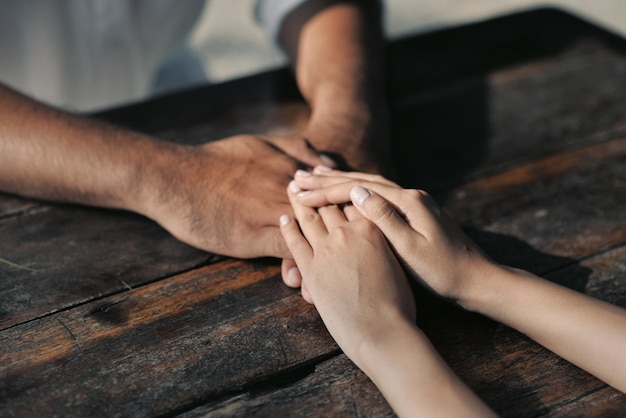 Manos cortadas de una pareja sosteniendo las manos en la mesa