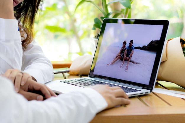 Manos cortadas de una pareja usando una computadora portátil en la mesa