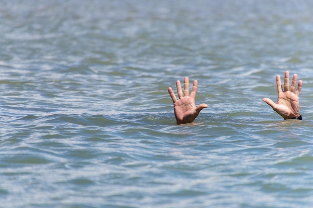 Manos cortadas de una persona que se ahoga en un lago