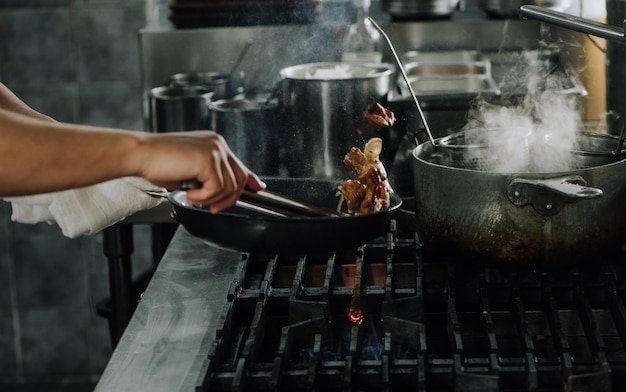 Manos cortadas de una persona que prepara comida en la estufa