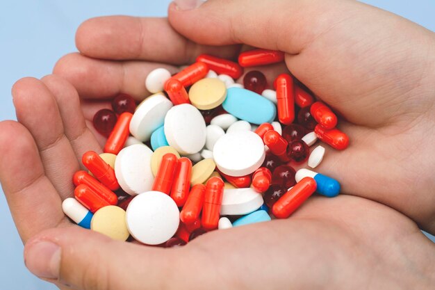 Manos cortadas de una persona que sostiene pastillas multicolores