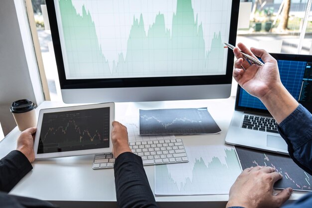 Manos cortadas de personas discutiendo sobre la computadora en la mesa