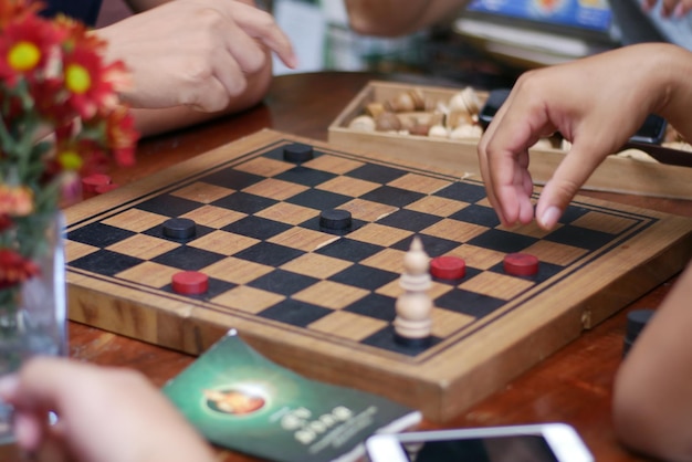 Manos cortadas de personas jugando a un juego de mesa en la mesa