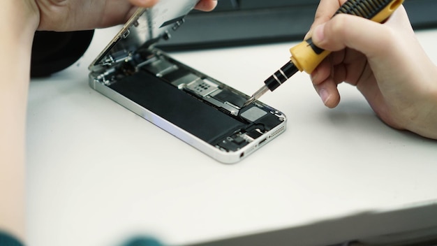 Manos cortadas reparando el teléfono móvil en la mesa.