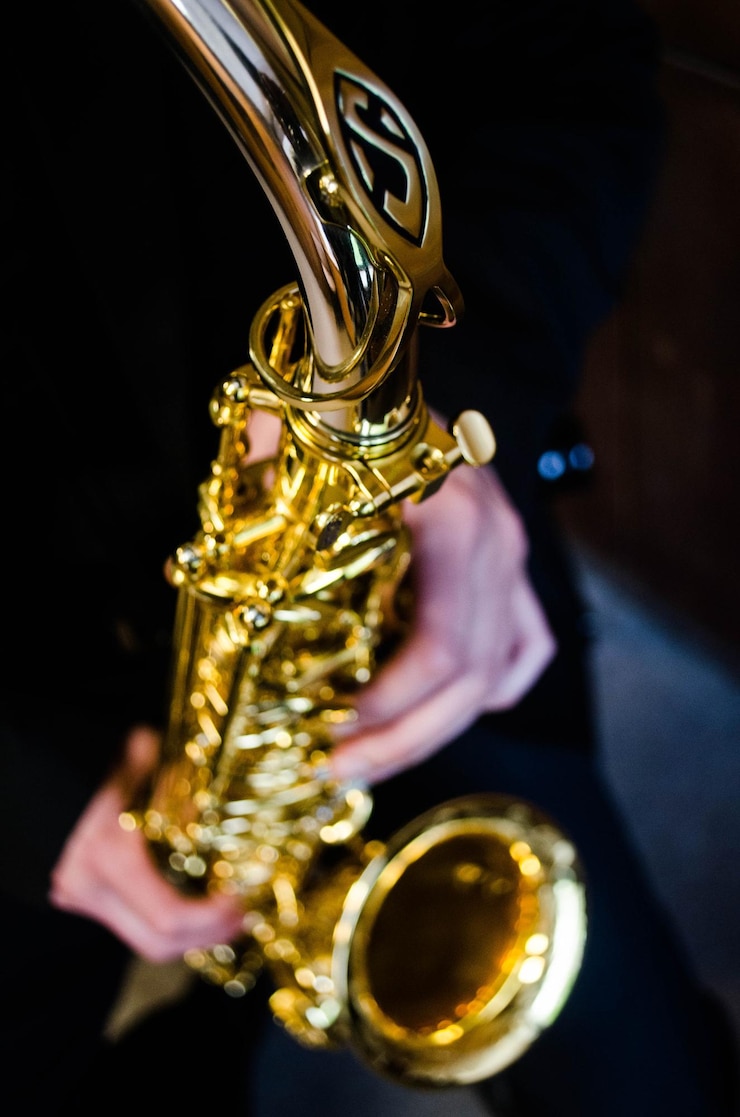 Foto manos cortadas con saxofón en el cuarto oscuro.