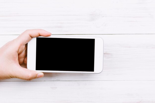 Foto manos cortadas con teléfono móvil en la mesa