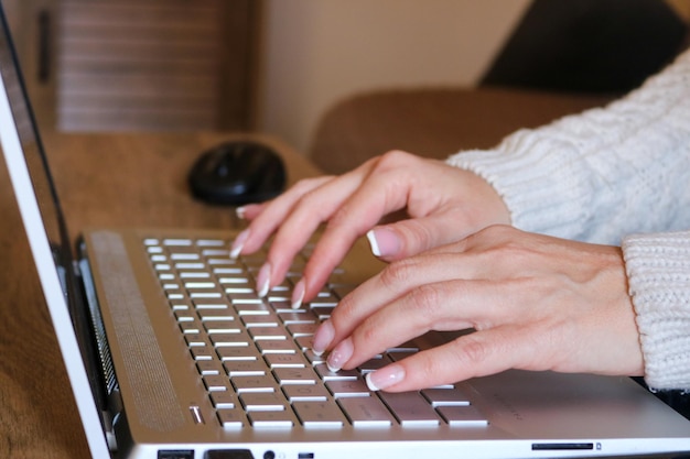 Manos cortadas usando una computadora portátil en casa