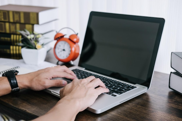 Manos cortadas usando una computadora portátil en la mesa