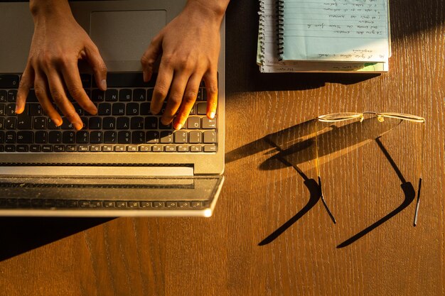 Foto manos cortadas usando una computadora portátil en la mesa