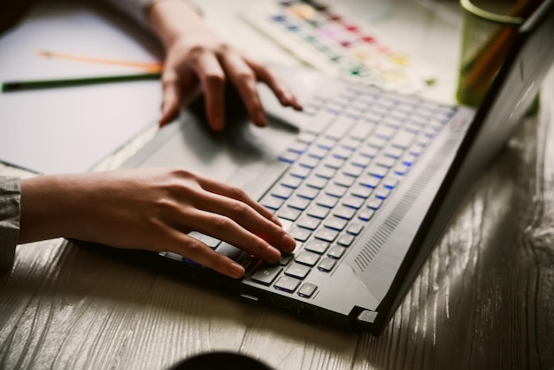 Manos cortadas usando una computadora portátil en la mesa