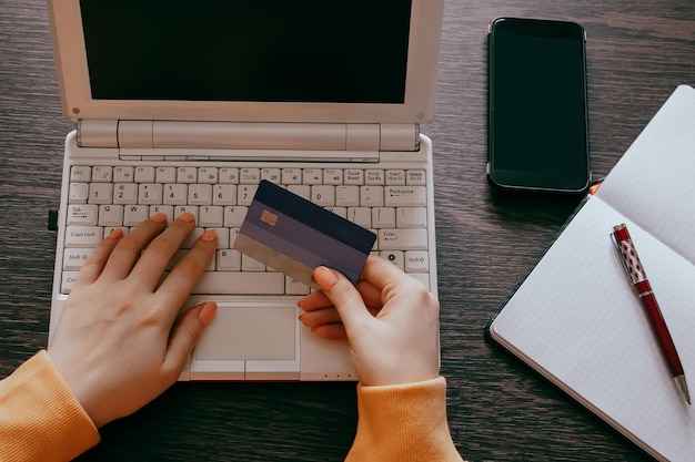 Manos cortadas usando una computadora portátil en la mesa
