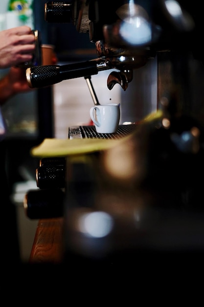 Manos cortadas vertiendo café en una taza en una cafetería
