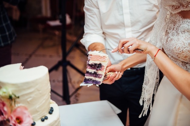 Manos cortando un delicioso pastel de bodas blanco