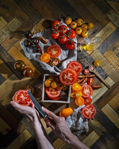 Foto manos cortando tomates sobre fondo de madera.