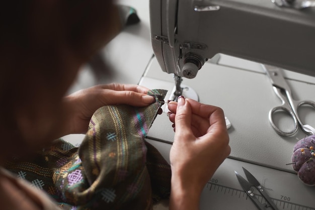 Manos cosiendo detalle de ropa en máquina de coser eléctrica