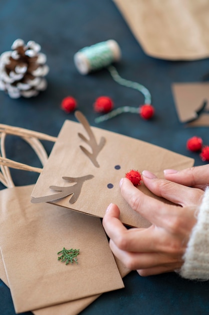 Manos creando adorable reno decorado bolsa de regalo de navidad