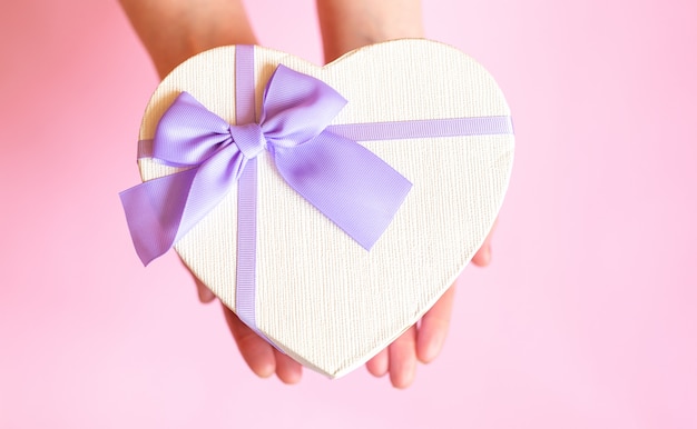 Las manos de una dama con caja de regalo en una superficie para el Día de San Valentín