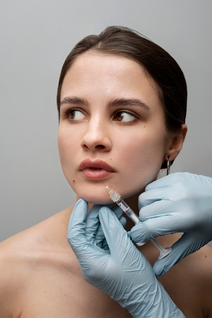 Foto manos dando rellenos de labios de mujer por inyección