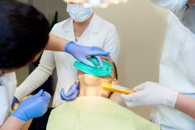 Las manos de un dentista cerca de la boca abierta de un joven.