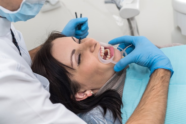 Manos de dentista con instrumentos y primer plano de la cara del paciente