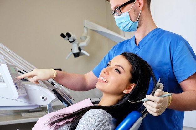 Manos de un dentista trabajando en una paciente joven con herramientas dentales.